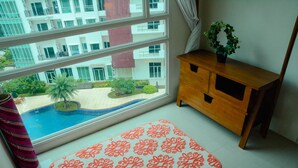 Ein Zimmer mit großem Fenster, einem Holfachschrank und einem gemusterten Teppich.