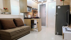 A compact living space with a sofa, kitchenette, and a TV.