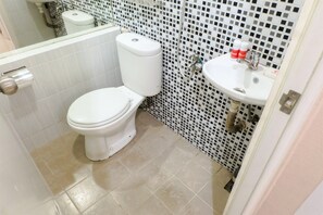 A bathroom with a toilet, sink, and tiled floor.