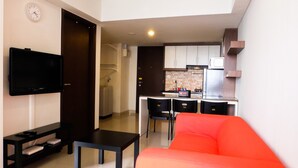 Un espacio habitable compacto con kitchenette, televisor de pantalla plana, sofá y zona de comedor.