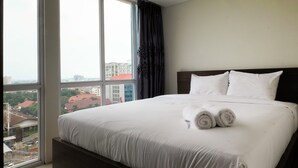 Una habitación de hotel con una cama grande, ropa de cama blanca y vistas a edificios a través de una ventana.