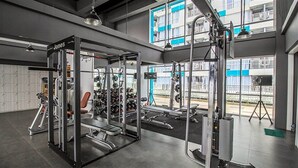 Un gimnasio con equipo de levantamiento de pesas, bancos y una estructura para sentadillas.