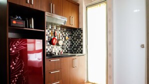 A modern kitchen with wooden cabinets, a stainless steel range hood, and a tiled backsplash. - Modern Room Bassura Apartment With Direct Access To Shopping Center (Jakarta)