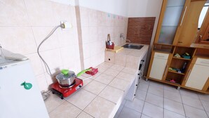 A kitchen with a portable stove, a sink, and a wooden cabinet with drawers.