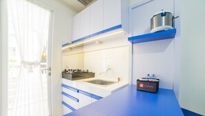 Cocina moderna con armarios blancos, encimera azul, un lavamanos, una estufa y una caja de travelio sobre la encimera.