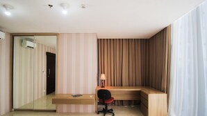 Quarto moderno com escrivaninha de madeira, uma cadeira, um abajur e um espelho grande.