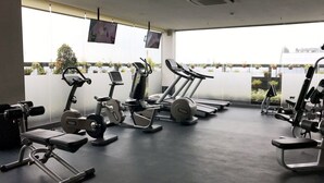 Uma academia com equipamentos de cardio, bancos de peso e halteres.