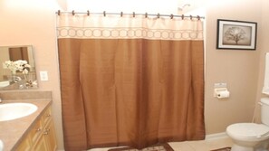 A bathroom with a brown shower curtain, a sink, a toilet, and a framed picture on the wall. - Tr314 - Terrace Ridge - 2 Bed 2 Baths Condo (Davenport)