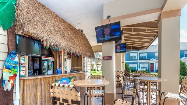 A bar area with a thatched roof, a TV screen, and outdoor seating. - Lc2604 - Villas at Seven Dwarfs Lane - 4 Bed 3 Baths Townhome (Kissimmee)