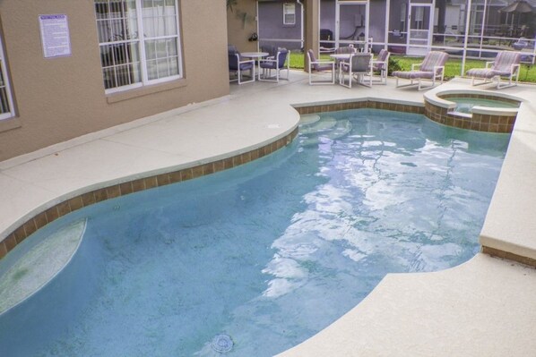 A swimming pool with a curved edge, surrounded by lounge chairs and a patio area. - Ip60375 - Rolling Hills Estates - 4 Bed 3 Baths Villa (Kissimmee)