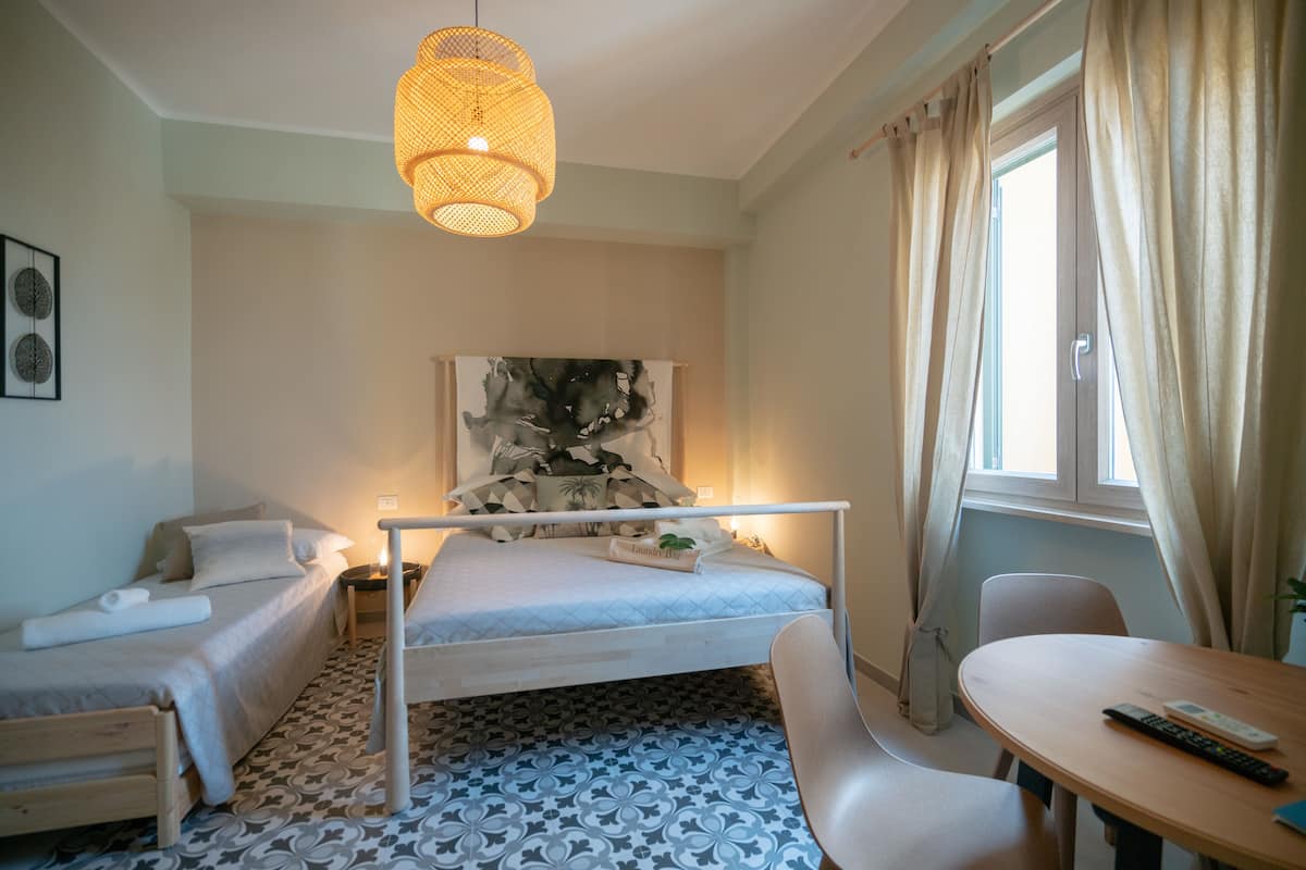 Een slaapkamer met een bed, nachtkastje, stoel en een kleintje tafeltje met een afstandsbediening.
