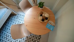 Un tavolo rotondo in legno con una pianta in vaso, un piatto di snack e una brochure.