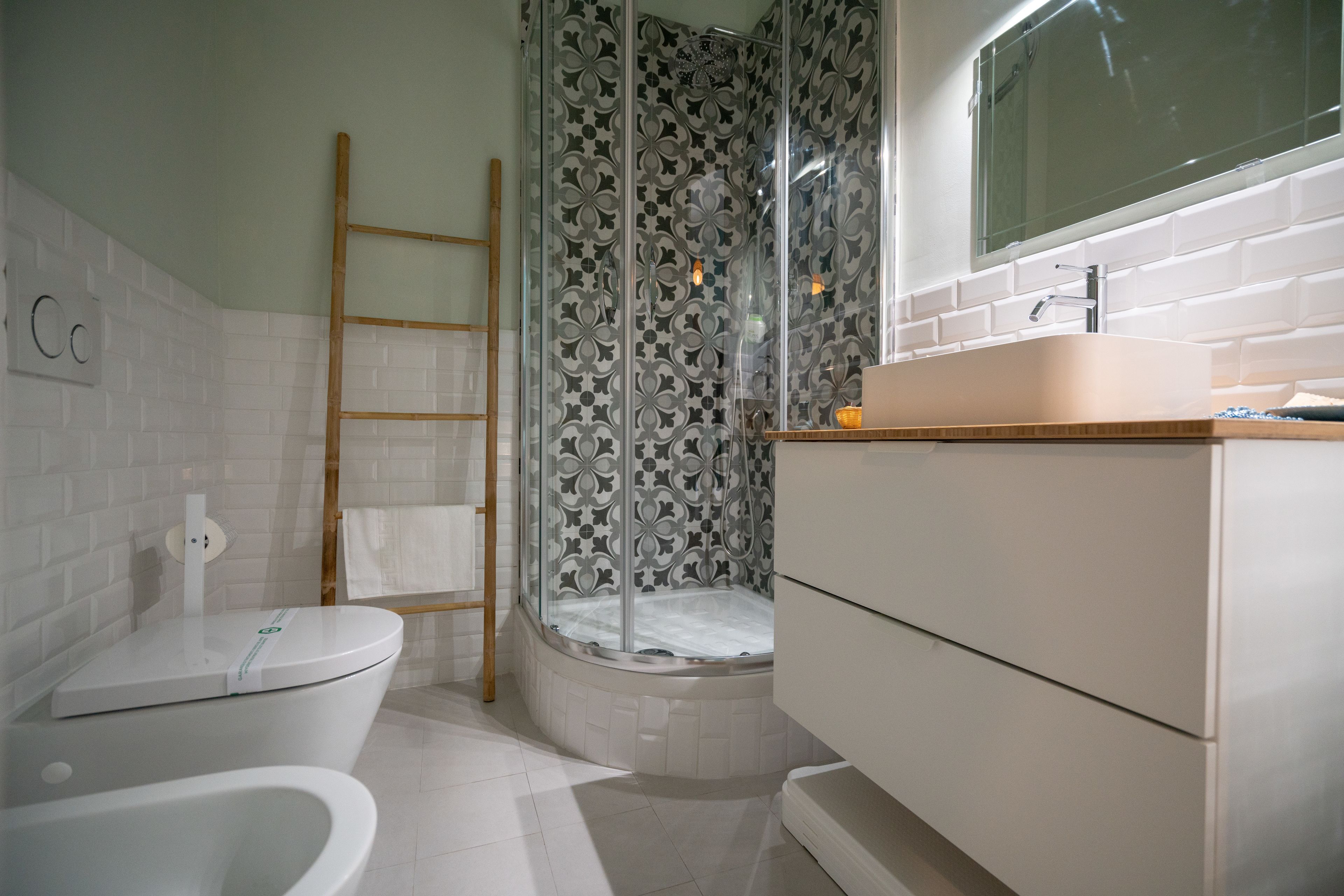 Un baño moderno con inodoro, ducha con puerta de vidrio y lavabo con espejo arriba.