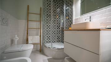 Un baño moderno con inodoro, ducha con puerta de vidrio y lavabo con espejo arriba.