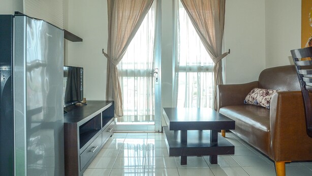 A living room with a flat-screen TV, a sofa, a coffee table, and a dining table. - Apartment Taman Semanan Cengkareng Great Value (Jakarta)