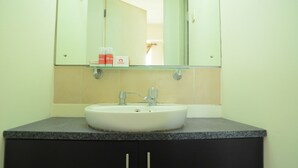 A bathroom with a white sink, a mirror above it, and a shelf with toiletries. - Apartment Taman Semanan Cengkareng Great Value (Jakarta)