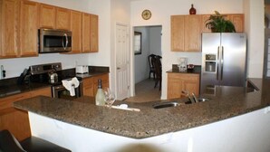 A kitchen with granite countertops, wooden cabinets, stainless steel appliances, and a central island. - Ip60402 - Sand Hill - 5 Bed 3 Baths Villa (Davenport)