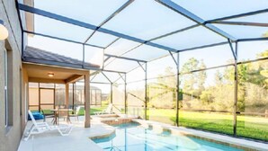 Une piscine dotée d’un patio couvert, de chaises longues et offrant une vue sur le paysage environnant.
