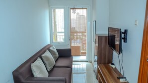 A living room with a brown sofa, a TV, and a wooden coffee table. - Best Price Grand Palace Near JIEXPO Kemayoran (Jakarta)