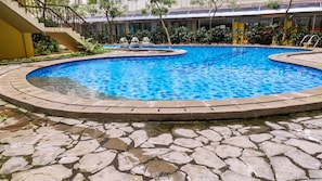 Ein kreisförmiger Pool mit Steinumrandung, umgeben von einer Steinterrasse.