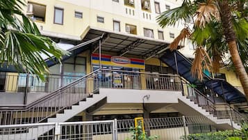 A multi-story building with a prominent Indomaret sign, a staircase, and a palm tree.