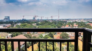 Ein Balkon mit Blick auf eine Stadtlandschaft, darunter Wohngebäude und Baukräne.