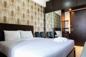 A hotel room with a large bed, a wardrobe, a mirror, and a seating area with chairs. - Good Studio 23 Kebagusan City Apartment (Jakarta)