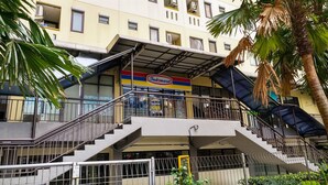 A multi-story building with a prominent Indomaret sign, a staircase, and a palm tree. - Good Studio 23 Kebagusan City Apartment (Jakarta)