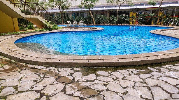A circular pool with a stone border, surrounded by a stone patio. - Good Studio 23 Kebagusan City Apartment (Jakarta)