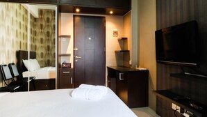 A hotel room with a large bed, a desk with a computer, a TV, and a mirror. - Good Studio 23 Kebagusan City Apartment (Jakarta)