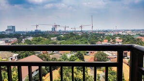 A balcony with a view of a cityscape, including residential buildings and construction cranes. - Good Studio 23 Kebagusan City Apartment (Jakarta)