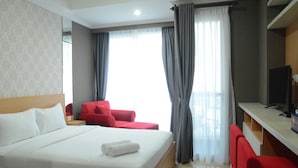 A hotel room with a bed, a desk, a TV, and a red chair. - Exclusive Studio at Menteng Park Apartment (Jakarta)