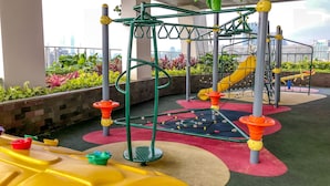 An outdoor play area with a climbing structure, slides, and colorful flooring. - Exclusive Studio at Menteng Park Apartment (Jakarta)