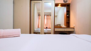 Ett hotellrum med en säng, en spegel, ett nattduksbord och en garderob.