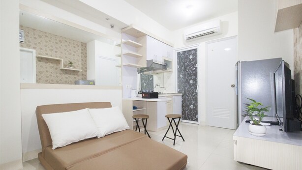 Une chambre à coucher de taille réduite, comprenant un lit, un petit bureau et un téléviseur.