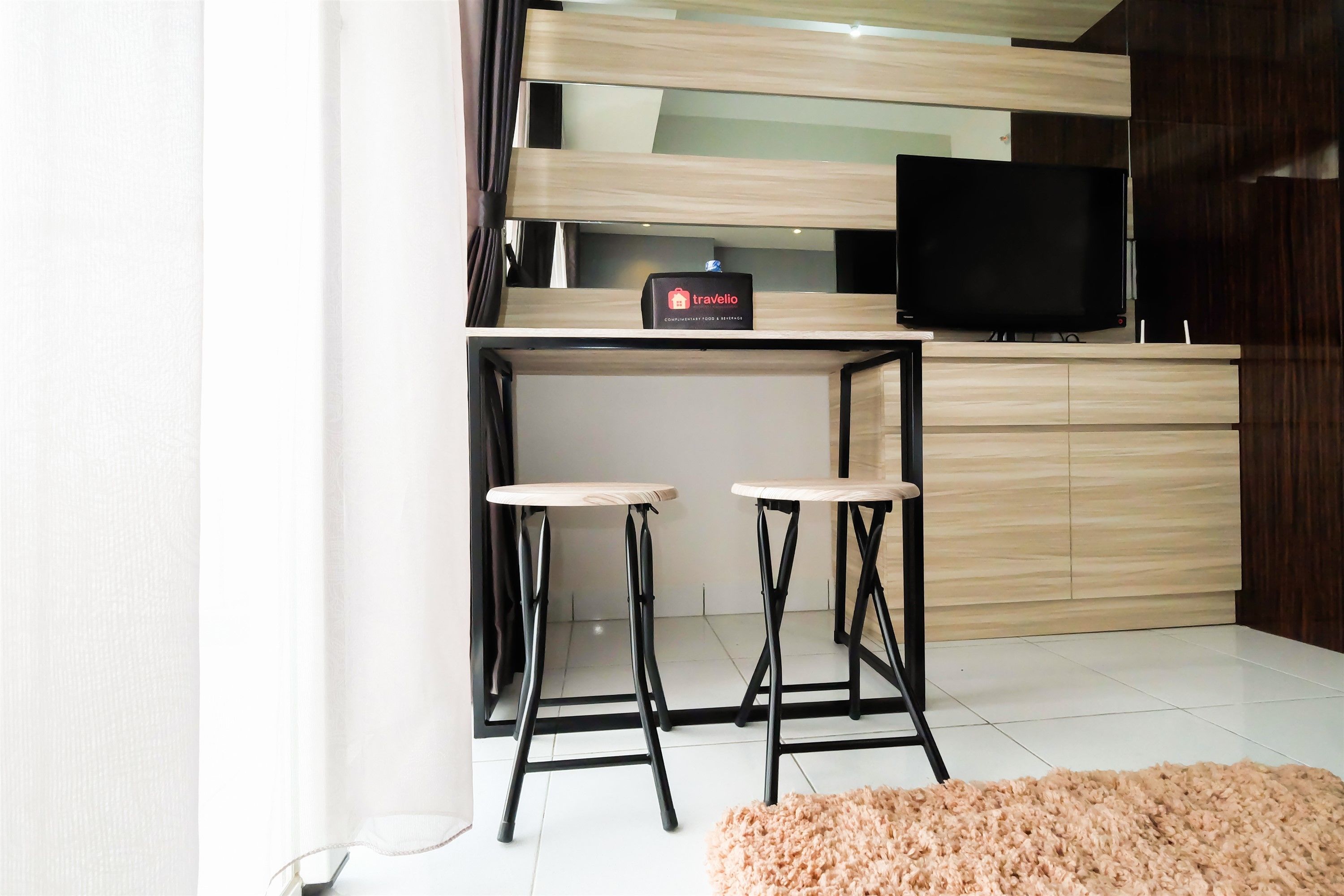 Una cocina moderna con encimera de madera, un televisor negro y dos taburetes de bar.