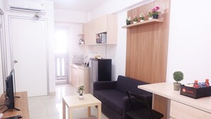 Un espacio habitable compacto con kitchenette, un sofá, una mesita y un televisor.