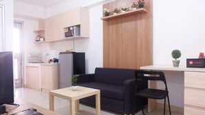 Un espacio habitable compacto con kitchenette, un sofá, una mesa de comedor y un televisor.