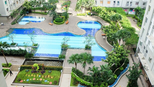 Un área de piscina en la azotea con varias piscinas, rodeada de exuberante vegetación y palmeras.
