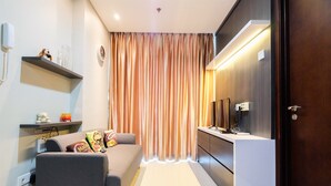 A modern hotel room with a sofa, a desk, a mirror, and a curtain. - Best Price Brooklyn Apartment near IKEA Alam Sutera (South Tangerang)