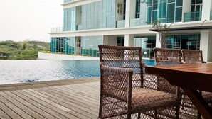 A modern hotel with a pool area, featuring wicker furniture and a view of the surrounding landscape. - Best Price Brooklyn Apartment near IKEA Alam Sutera (South Tangerang)