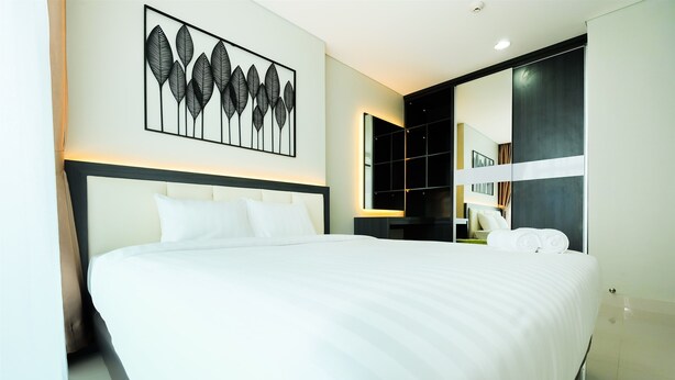 A modern hotel room with a large bed, a wall-mounted artwork, a built-in wardrobe, and a large mirror. - Best Price Brooklyn Apartment near IKEA Alam Sutera (South Tangerang)