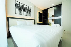 A modern hotel room with a large bed, a wall-mounted artwork, a built-in wardrobe, and a large mirror. - Best Price Brooklyn Apartment near IKEA Alam Sutera (South Tangerang)