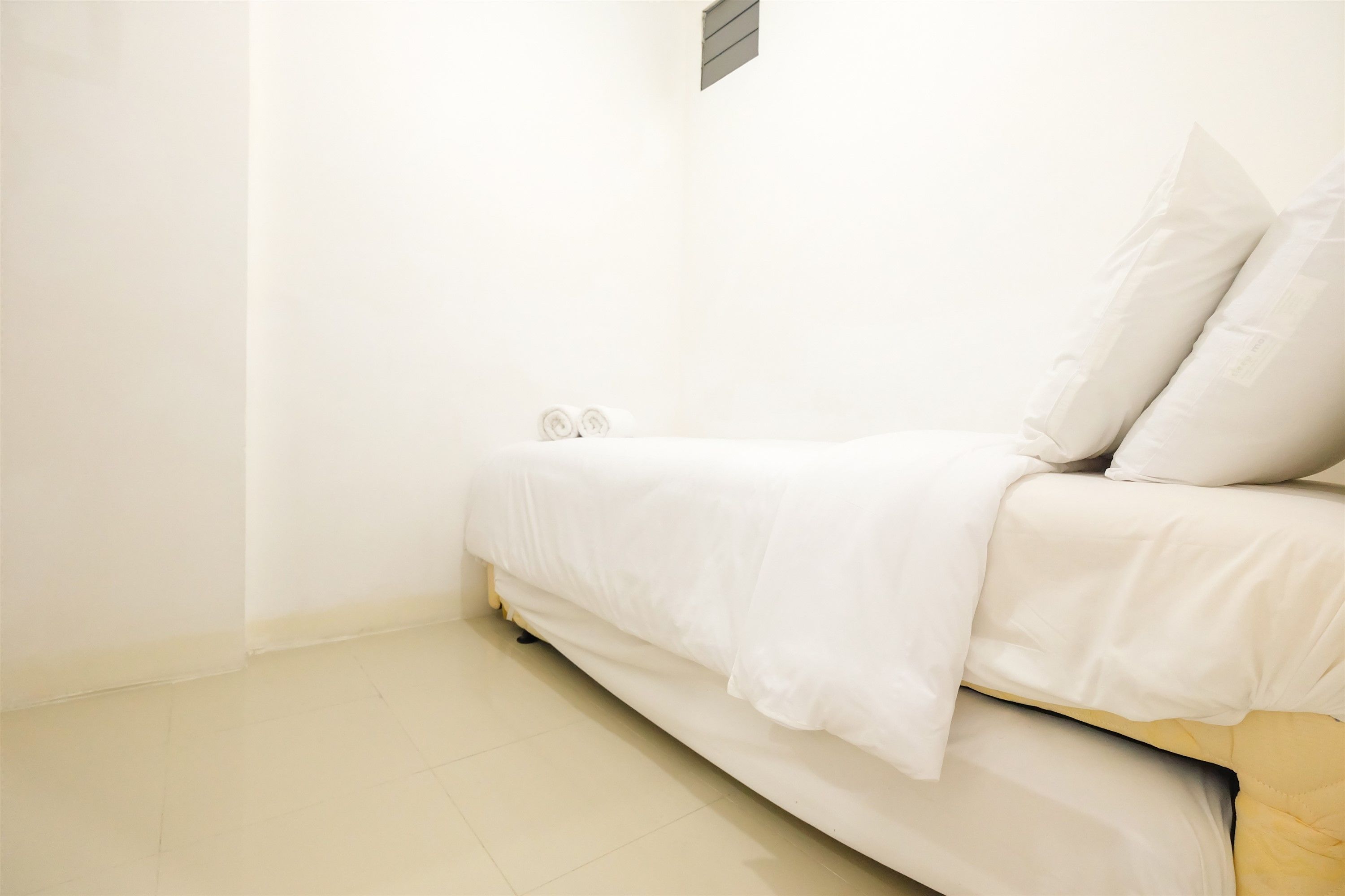 Une petite chambre à coucher, bien rangée, avec un lit simple, une table de chevet et un radiateur fixé au mur.