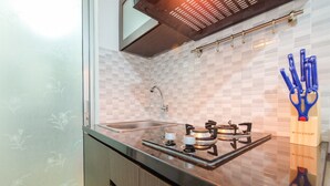 A kitchen with a gas stove, sink, and a window with a view. - Enjoy Jakarta! Bassura City Apartment (Jakarta)