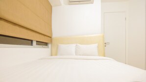 A hotel room with a bed, a door, and an air conditioning unit. - Enjoy Jakarta! Bassura City Apartment (Jakarta)