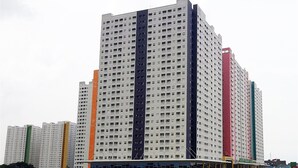 A multi-story residential building with a uniform facade, large windows, and a flat roof. - Easy Access to Mall Green Pramuka Apartment (Jakarta)