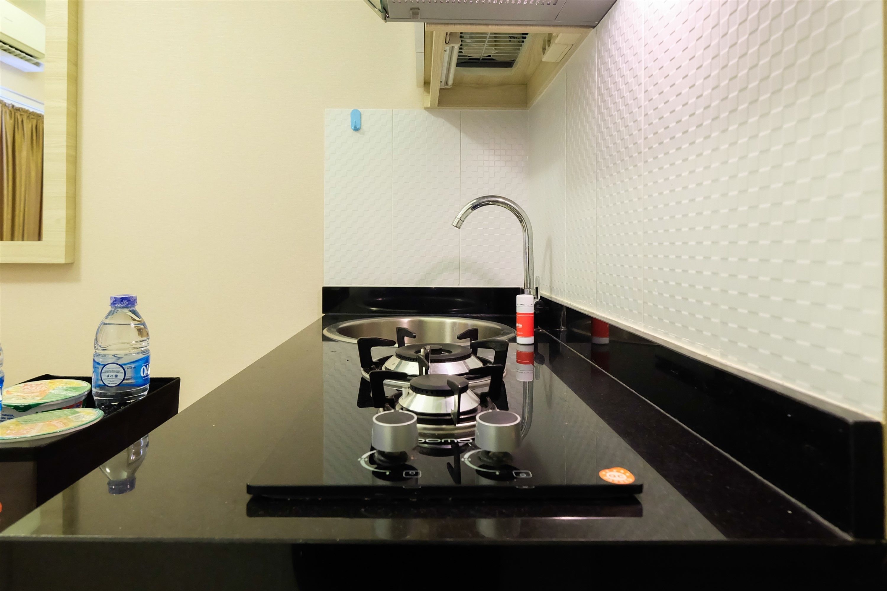 A kitchen with a gas stove, stainless steel sink, and a water bottle on the counter.