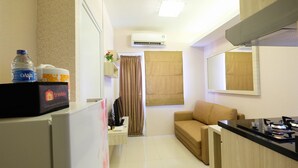 A compact hotel room with a kitchenette, a sofa, a dining table, and a small desk. - Easy Access to Mall Green Pramuka Apartment (Jakarta)
