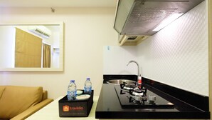 A compact kitchenette with a gas stove, sink, and a box of complimentary travel food and beverages. - Easy Access to Mall Green Pramuka Apartment (Jakarta)